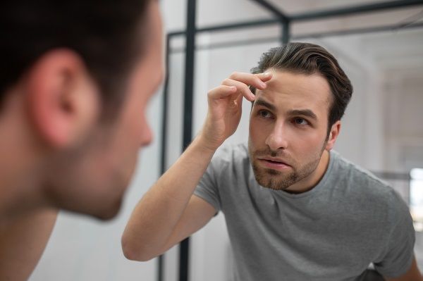 Hombre con alopecia mirándose en espejo