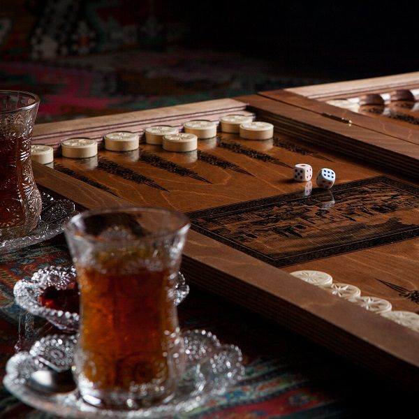 Vaso de té con backgammon y mermelada en la mesa de alfombra