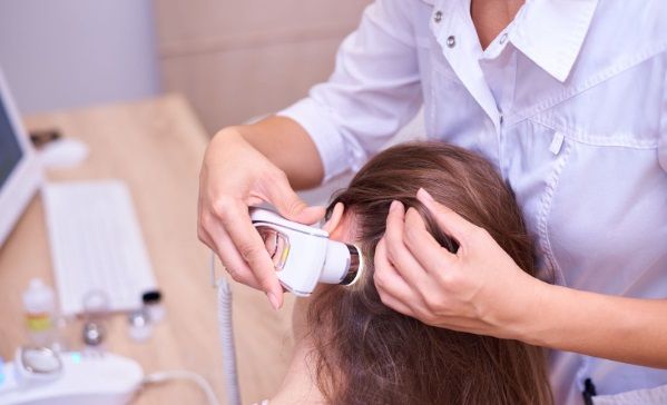 Revisión del cabello de una paciente por parte de la tricóloga con aparato especializado