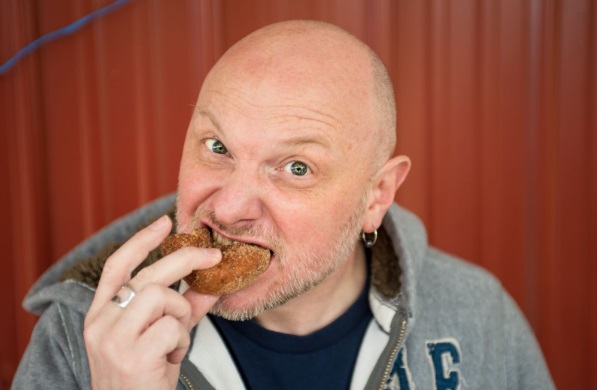 Hombre con calvicie comiendo un alimento alto en grasas saturadas representando la mala alimentación y su posible relación con la calvicie