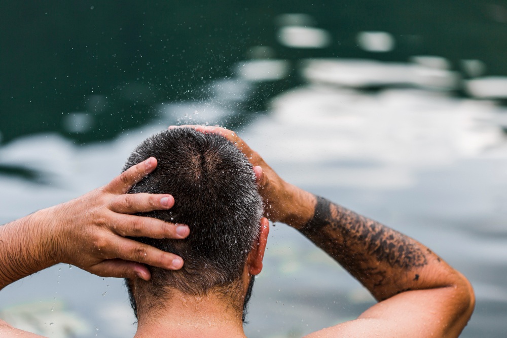 Hombre lavándose el pelo y refrescándose