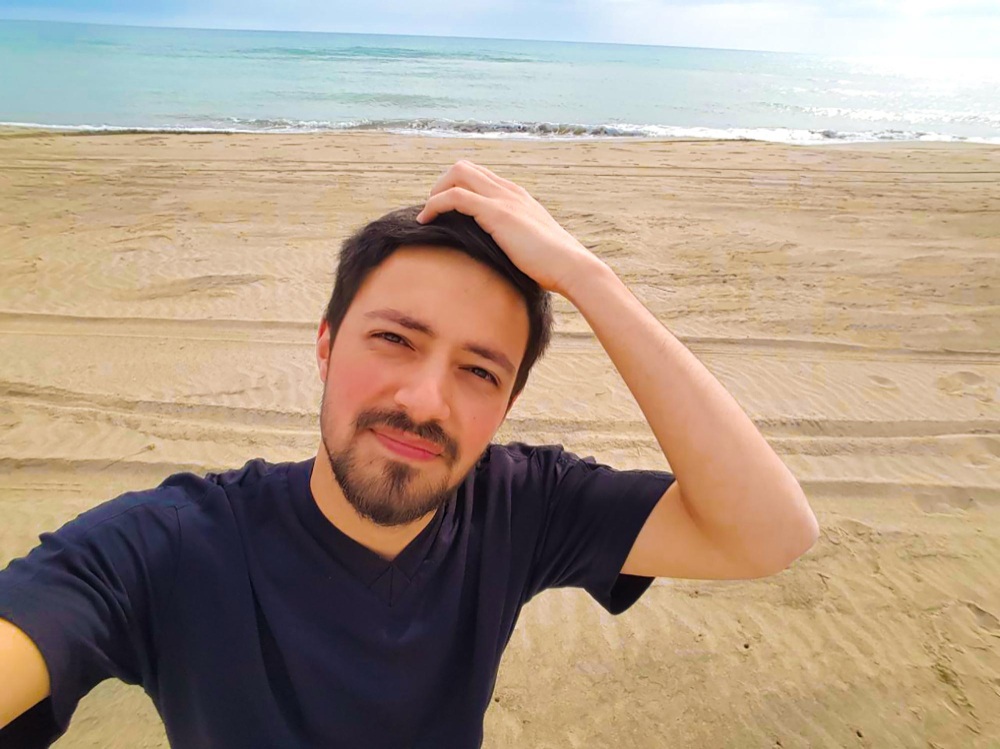 Hombre en la playa tocándose el pelo feliz