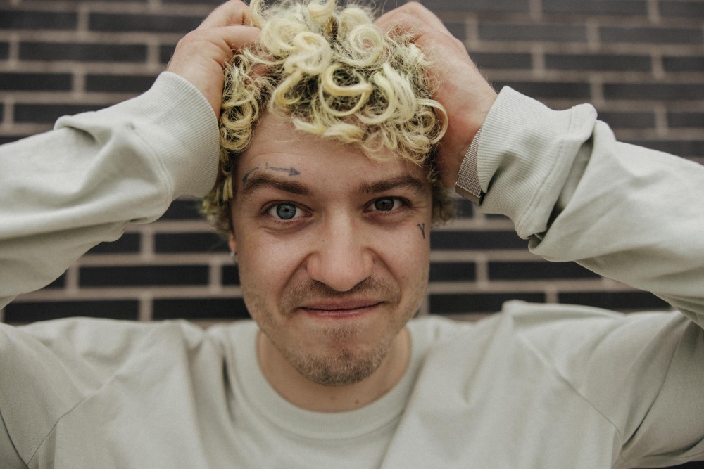 Hombre teñido sonriendo tocándose el cabello