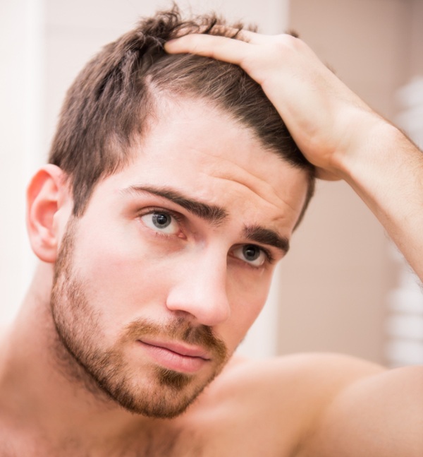 Hombre tocándose el pelo pensando cómo prevenir al caída de su cabello