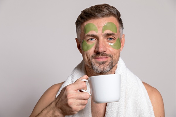 Hombre con cosmético en la cara con una taza blanca en la mano