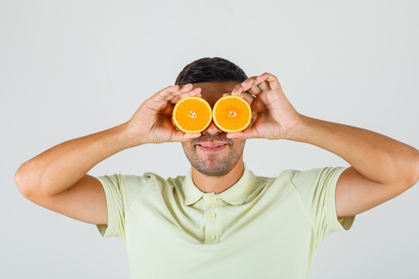 Hombre con media naranja en cada ojo como si fuera unos prismáticos