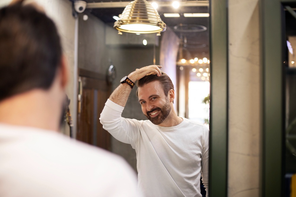Hombre tocándose el pelo frente al espejo representando la protección del cabello