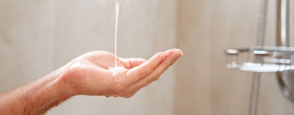 Champú cayendo en una mano en la ducha