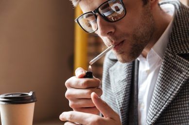 Hombre encendiéndose un cigarrillo representando que fumar aumenta la caída del cabello