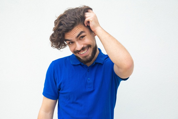 Hombre con barba feliz tocándose el pelo largo de la cabeza