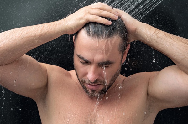 Hombre enjuagándose el pelo en la ducha